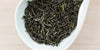 A white dish containing dry jasmine tea leaves.