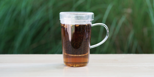 A glass cup with superior earl grey brewing in the nested glass infuser.