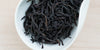 A white dish containing dry Phoenix oolong tea leaves.