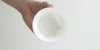 A hand holds the bowl of a gaiwan up to the light, showing how the light shines through the thin porcelain.