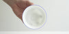 A hand holds the bowl of a gaiwan up to the light, showing how the light shines through the thin porcelain.
