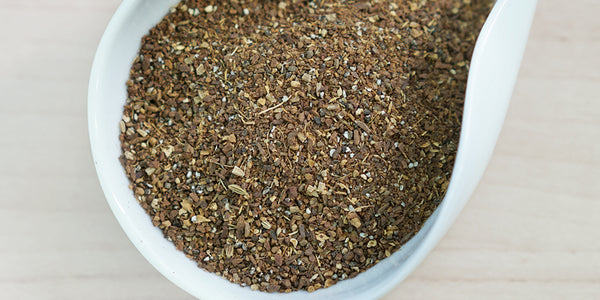 A white dish containing dry masala chai spices.