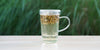 A glass cup with chamomile flowers brewing in the nested glass infuser.
