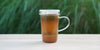 A glass cup with ginger lemongrass brewing in the nested glass infuser.