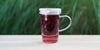 A glass cup with hibiscus brewing in the nested glass infuser.