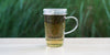 A glass cup with peppermint rose brewing in the nested glass infuser.