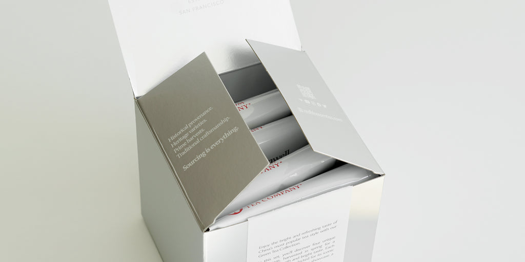 A silver box with 4 white bags of tea inside.