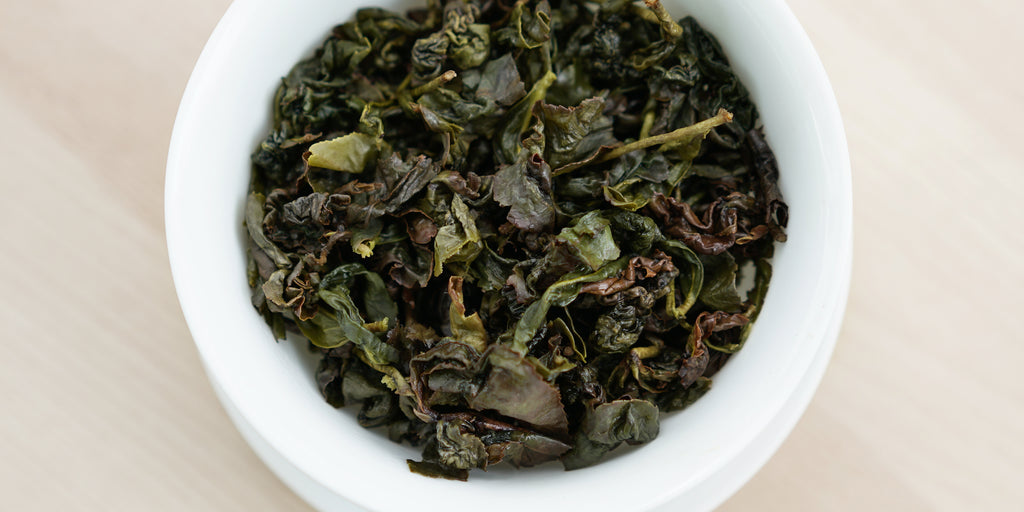 A top-down photo of brewed Formosa oolong tea leaves in a gaiwan.