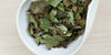 A white dish containing dry white tea leaves.