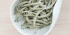 A white dish containing dry white tea leaves.