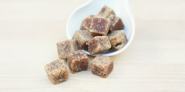 A white dish with cubes of winter melon sugar overflowing from it.