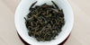 A top-down photo of brewed Phoenix oolong tea leaves in a gaiwan.
